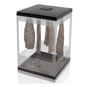Countertop meat dehydrator with several beef jerky strips hanging inside a clear cabinet, drying vertically under a black top rim.