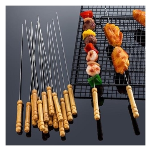 Assorted meat and vegetable skewers with wooden handles placed beside a barbecue grill, some skewers waiting and others cooking on the rack.